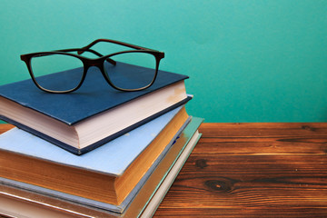  pile of old books with glasses panorma, good copy space  on blue background