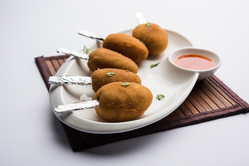 Crispy Veg lollipop recipe made using boiled potato with spices covered with corn flour and bread crumbs coating and then deep fried, served with toothpick or ice cream stock inserted in it with sauce