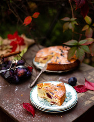 tasty homemade plum cake slice on vintage plates on brown rustic table