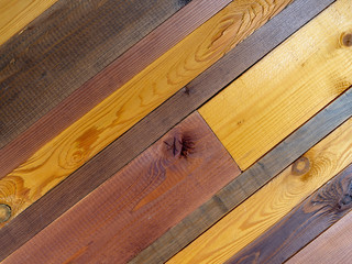 A wooden table made of planks of various sizes and treated with different colors of stain: yellow, oak, nutty. Background with diagonal lines