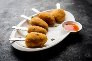 Crispy Veg lollipop recipe made using boiled potato with spices covered with corn flour and bread crumbs coating and then deep fried, served with toothpick or ice cream stock inserted in it with sauce