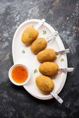 Crispy Veg lollipop recipe made using boiled potato with spices covered with corn flour and bread crumbs coating and then deep fried, served with toothpick or ice cream stock inserted in it with sauce