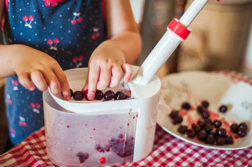 Women's hands remove bones from the cherry with a special device