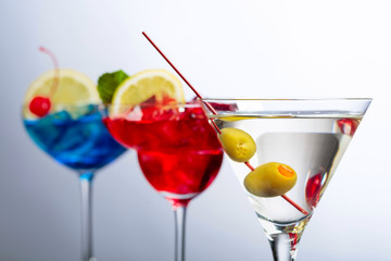 Two colorful cocktails and dry martini with green olives.