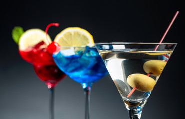 Two colorful cocktails and dry martini with green olives.
