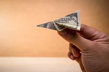 A man hand and folded paper planes origami made by USD notes/bills