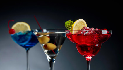 Two colorful cocktails and dry martini with green olives.