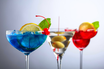 Two colorful cocktails and dry martini with green olives.