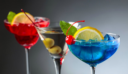 Two colorful cocktails and dry martini with green olives.