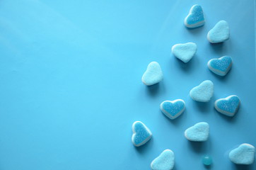 An assortment of colourful, festive sweets, lue marmalade in the shape of a heart on a blue background with a variety of caramels and candies, marshmallows. Abstract background. top view . copy space.
