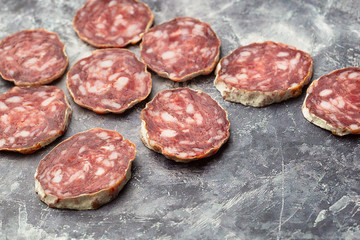 Traditional  thin dried sausage with slices on grey stone background
