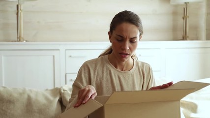 Dissatisfied female customer open cardboard box receive damaged parcel