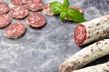 Traditional  thin dried sausage with slices on grey stone background