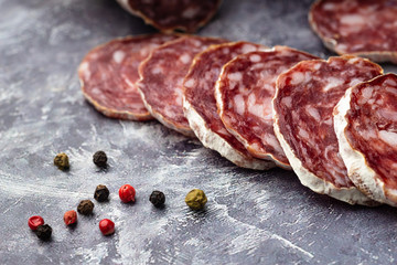 Traditional  thin dried sausage with slices on grey stone background