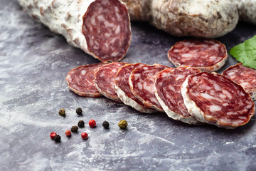 Traditional  thin dried sausage with slices on grey stone background