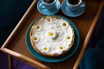 Top view - breakfast in bed a delicious cheesecake and two cups of coffee are on a wooden tray.