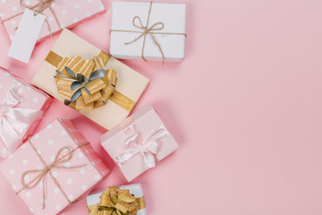 Gift box wrapped in pastel  paper with pink ribbon on pink surface. Top view  with copy space.