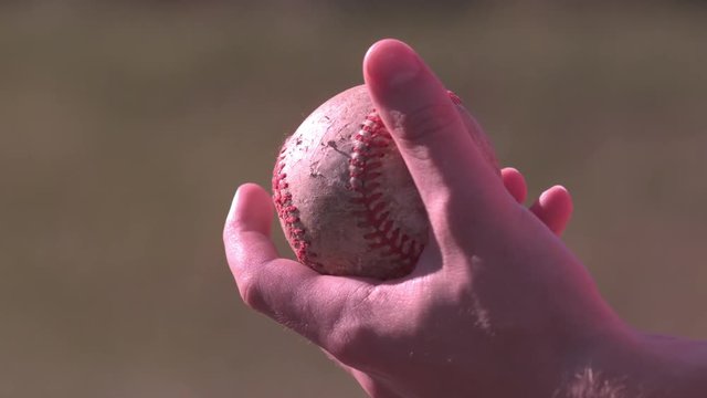 Hand gripping baseball in slow motion