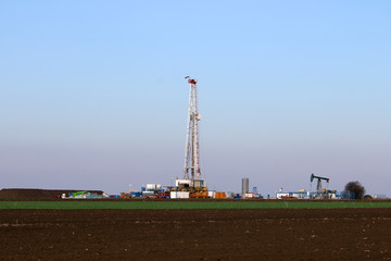Fototapeta na wymiar Oil and gas drilling rig and pump jack in oilfield