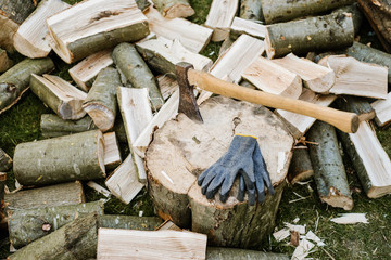 An axe on a log next to a chopped firewood