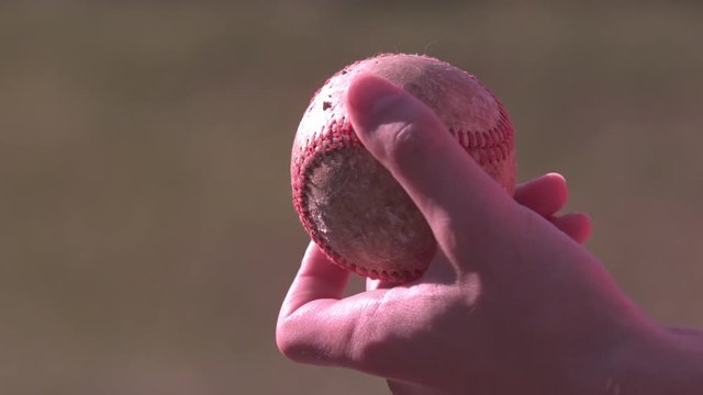 Old baseball in young boys hand slow motion