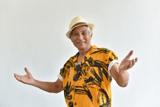 Cheerful Asian Senior Old Man, Confident And Smiling Elderly People With Welcome Gesture In Colorful Hawaii Shirt, Happy Retiree Citizen And Travel Concept.