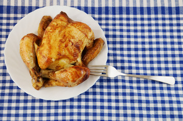 Grilled chicken in white plate on blue tablecloth