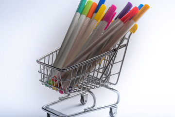 Close-up of shopping carts on white background..Trolley, Sale concept. Isolated over white background in a cart lies a colored markers.