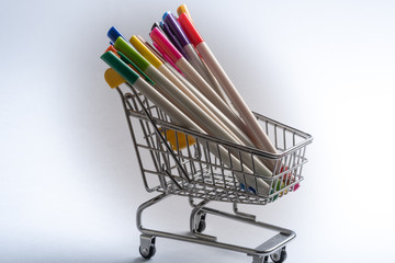 Close-up of shopping carts on white background..Trolley, Sale concept. Isolated over white background in a cart lies a colored markers.