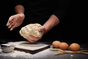 man Baker and his hands over the bread from whole wheat flour (to oven). flour, rustic style