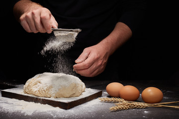 man Baker and his hands over the bread from whole wheat flour (to oven). flour, rustic style