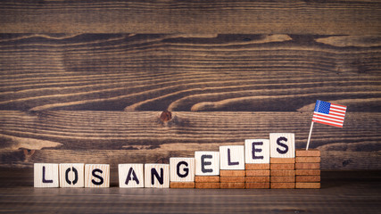Fototapeta premium Los Angeles, United States. Politics, economic and immigration concept. Wooden letters and flag on the office desk