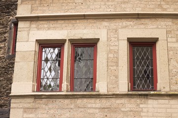 Three red windows in a stone facade (Germany, Europe)