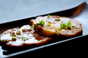 Japanese food style, Selective focus of sliced braised pork on black plate in restaurant (chashu), ready to eat or serve, on dark background