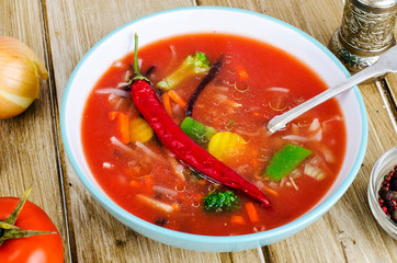 Spicy soup with tomatoes on wooden table