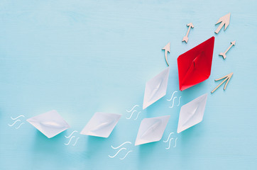 business. Leadership concept image with paper boats on blue wooden background. One leader guiding...