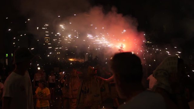 People Holding Lit Fireworks , At A Catholic Festival In Sitges, Spain. Crowds Of People Watching And Dancing, Celebrating All Over The Streets Of Sitges.  An Annual Event. Groups Dressed The Same.
