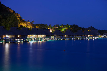 Fototapeta premium night landscape with houses over the water of the sea in backlight, Polynesia