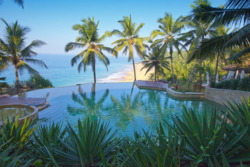 The pool on the edge of the rock overlooking the ocean and palm trees