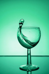 Splash of water in a glass on aqua background. Close up.