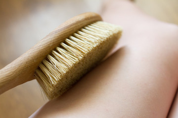 dry brush massage. girl massages her leg with a brush against cellulite