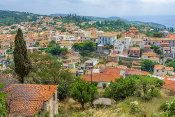 Fototapeta na wymiar Red roofs of historical Old Town with church. Cityscape of Greece on summer sunny day. Red rooftops of city background. Kymi, Greece. Evia Euboea island, Greece. Traveling location venue, location