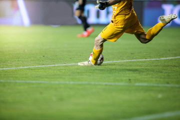 Details with the feet of a soccer goalkeeper kicking the ball during a match