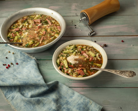 Cool summer gourmet soup with fresh vegetables on a wooden tray, denim napkin and wooden pepper shaker-mill. Serving on a wooden tray, tablespoons