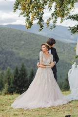Beautiful wedding couple staying over beautiful landscape. Bride in angel wings . Warm colors....
