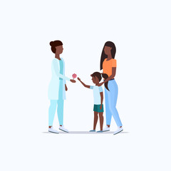 mother with daughter visiting african american doctor pediatrician giving lollipop to little girl consultation healthcare concept full length flat