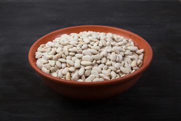 White beans in pottery on a black background. superfood