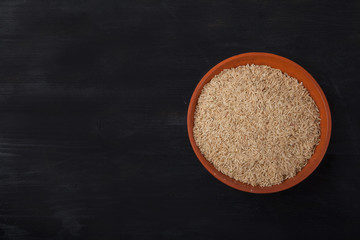 spelled groats in a clay cup on a black wooden background. superfood