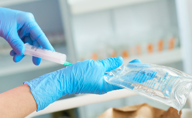 Nurse holding a medical syringe and solution for dropper in hands and putting medicine inside it. Injection preparation in hospital.