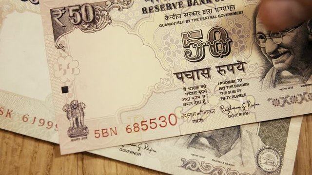 Closeup of hand stacking small amount of Indian rupee banknotes